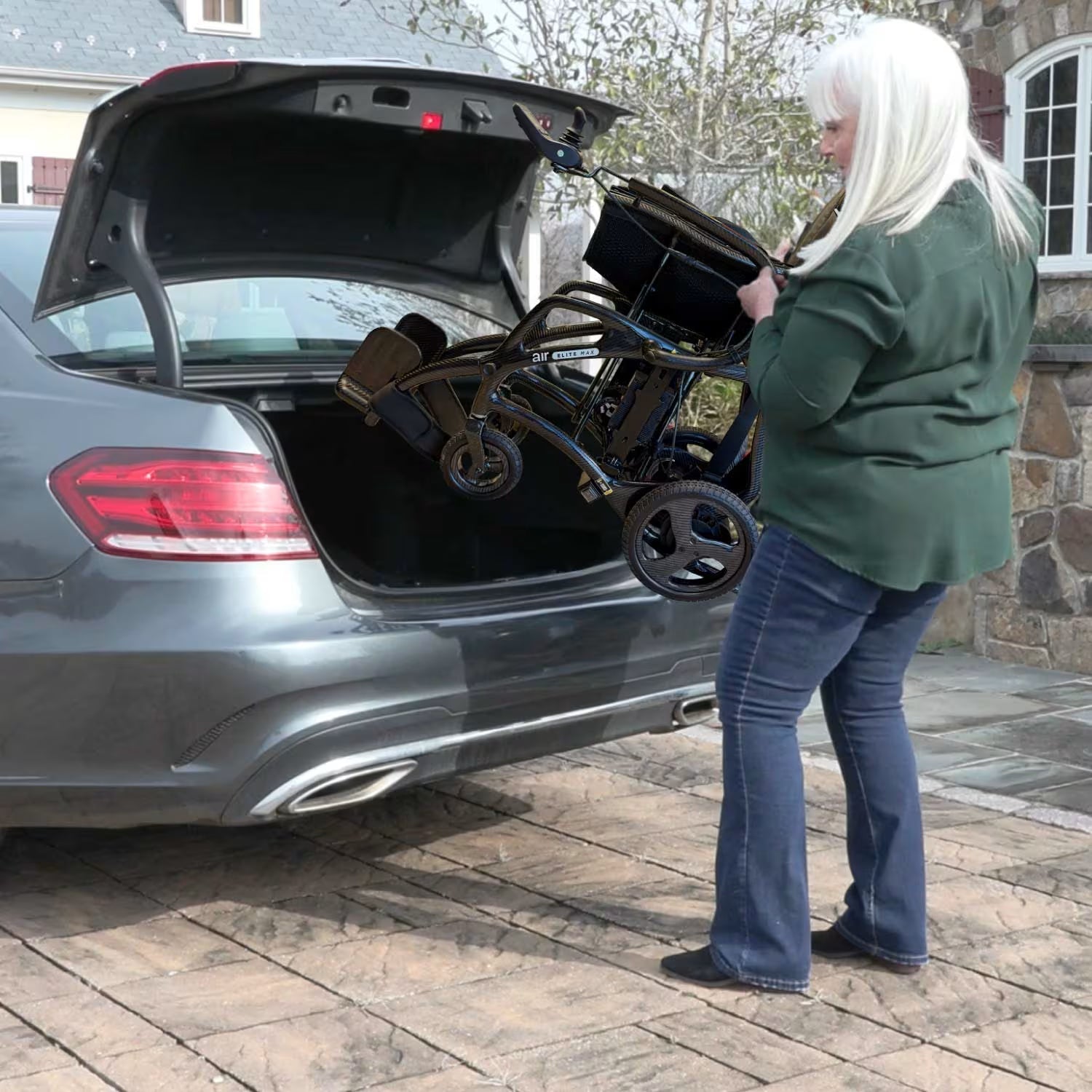 Woman lifting and storing the Journey Air Elite Max ultra-lightweight carbon fiber folding power chair into a car trunk for easy transport.